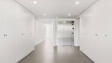 Un couloir moderne et bien éclairé, équipé de casiers et d’un ascenseur.