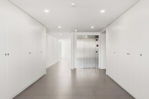 Un couloir moderne et bien éclairé, équipé de casiers et d’un ascenseur.