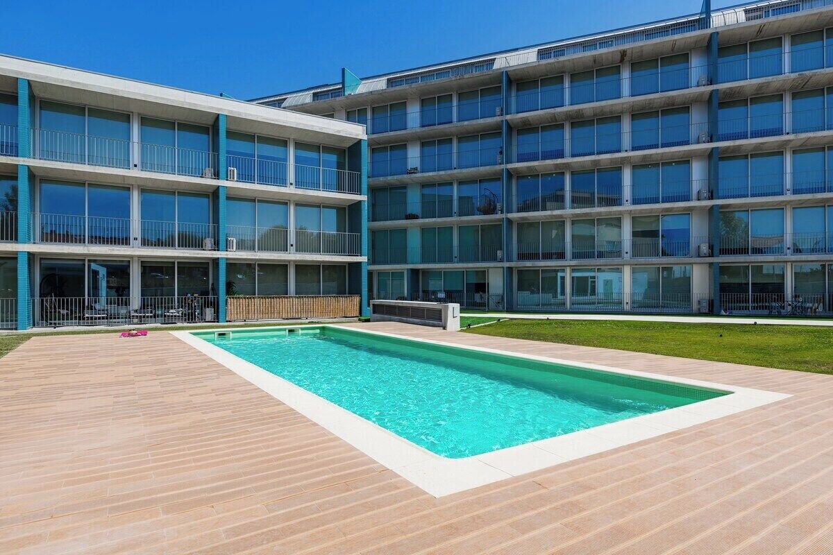 A modern building with a swimming pool and a wooden deck.