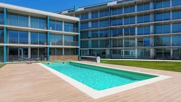 Un bâtiment moderne doté d’une piscine et d’une terrasse en bois.