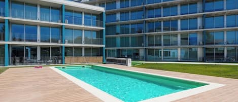 Un edificio moderno con piscina y terraza de madera.