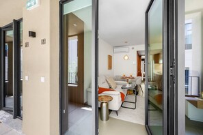 Eine moderne Wohnung mit Glastür, einem Wohnbereich mit Sofa, Couchtisch und Esstisch mit zwei Gläsern und einer Flasche.