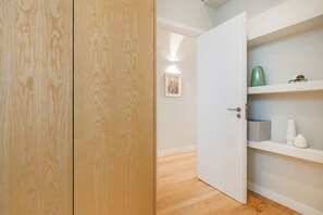 Ein Holzkleiderschrank, eine weiße Tür und ein Regal mit einem grünen und weißen Strauß Vasen.