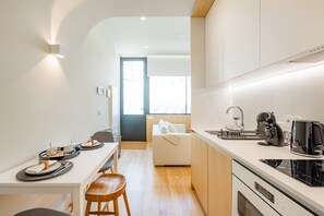 Eine moderne Küche mit Essbereich, einem Holzschemel und Blick in das Wohnzimmer.