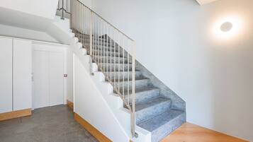 A staircase with a metal railing, carpeted steps, and a wooden floor.