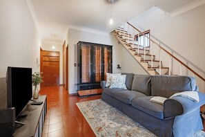 A living room with a sofa, a TV, a staircase, and a wooden door. - Ildefonso Oporto Stay (Porto)