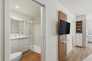 Un baño moderno con ducha de vidrio, lavamanos blanco y retrete.