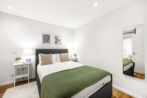 Ein modernes Schlafzimmer mit Bett, Nachttischen, einem Spiegel und Bildern an der Wand.