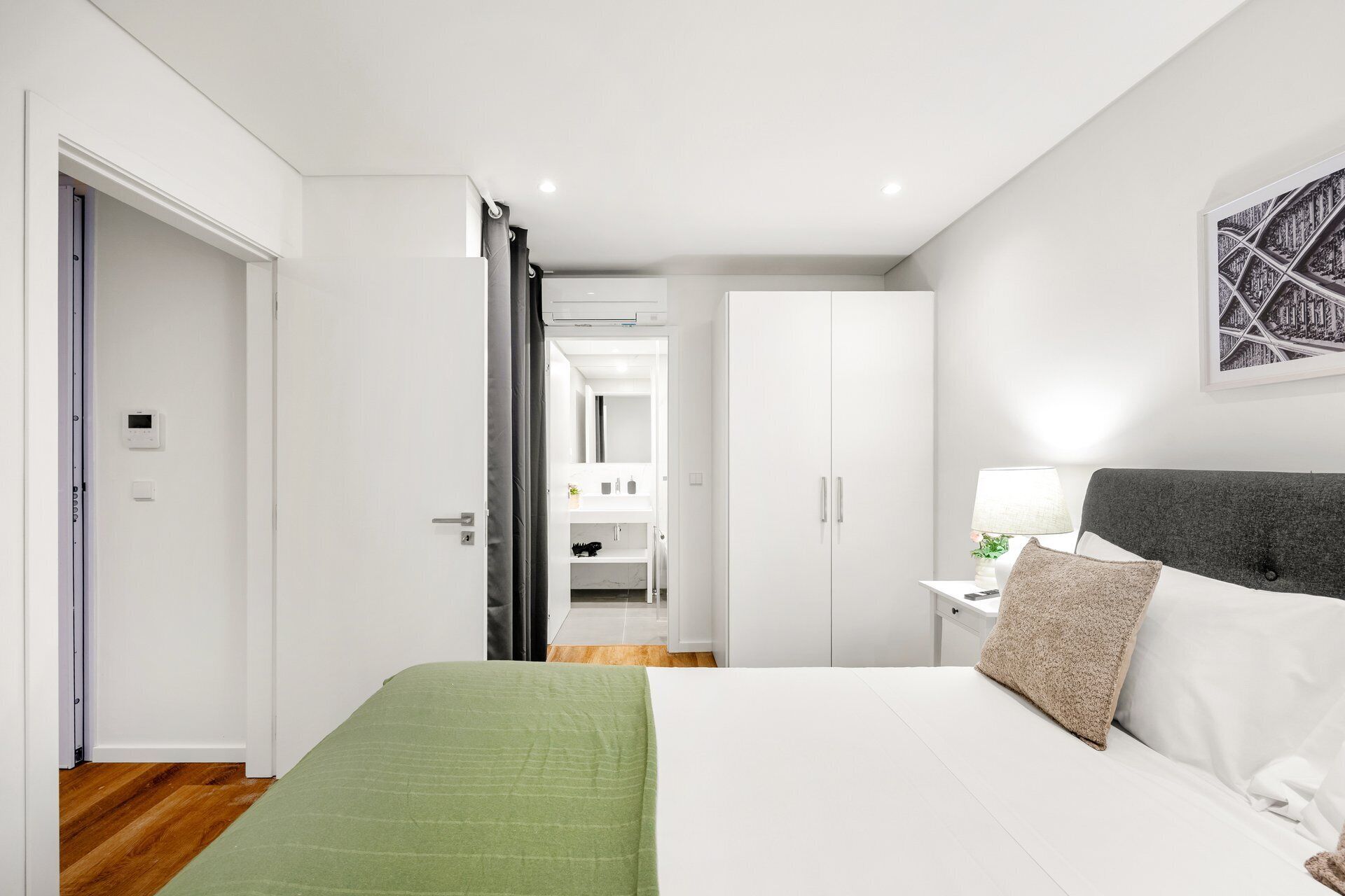 A bedroom with a bed, a nightstand, a lamp, and a wardrobe.