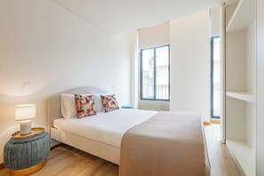 A bedroom with a bed, a bedside table with a lamp, a window, and a view of the outside. - Urban Style in Bonfim | Porto (Porto)