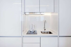 A modern kitchen with white cabinets, a stainless steel sink, and a coffee maker. - City Pocket | 111 Collection (Porto)