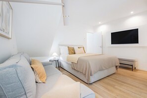 Ein modernes Schlafzimmer mit einem Bett, einem Sofa, einem Nachttisch und einem an der Wand montierten Fernseher.