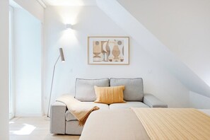 A modern, minimalist room with a grey sofa, a beige throw blanket, and a framed abstract artwork on the wall. - City Pocket | 111 Collection (Porto)
