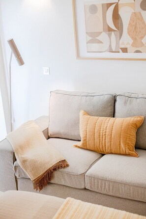 A modern living room with a grey sofa, a beige throw blanket, and a framed abstract artwork on the wall. - City Pocket | 111 Collection (Porto)