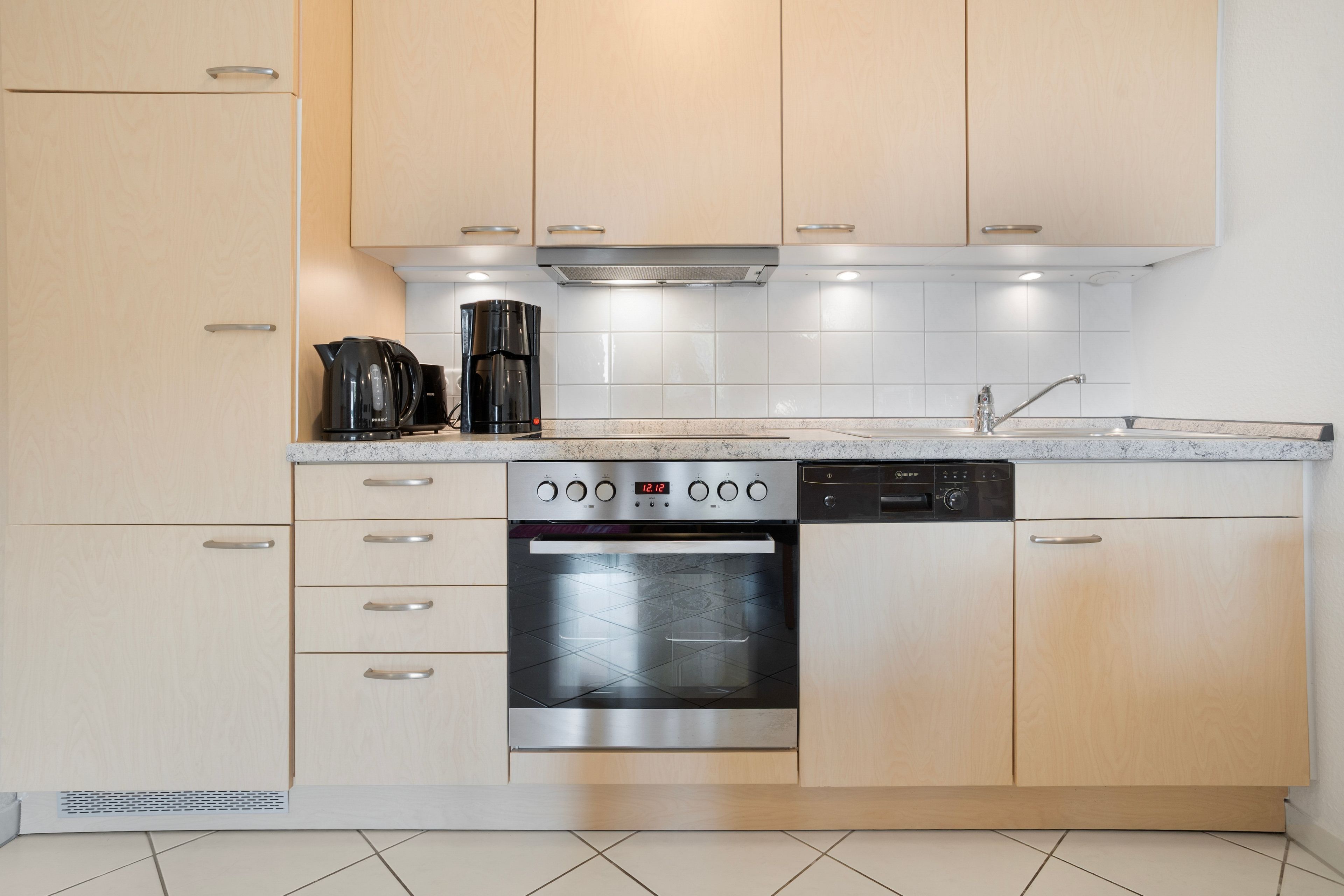 Una cocina moderna con electrodomésticos de acero inoxidable, lavavajillas y horno empotrado.