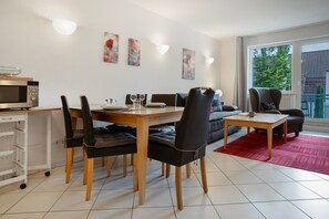 Ein moderner Essbereich mit einem Holztisch, schwarzen Sitzmöbeln, einer Mikrowelle und einer Couch.