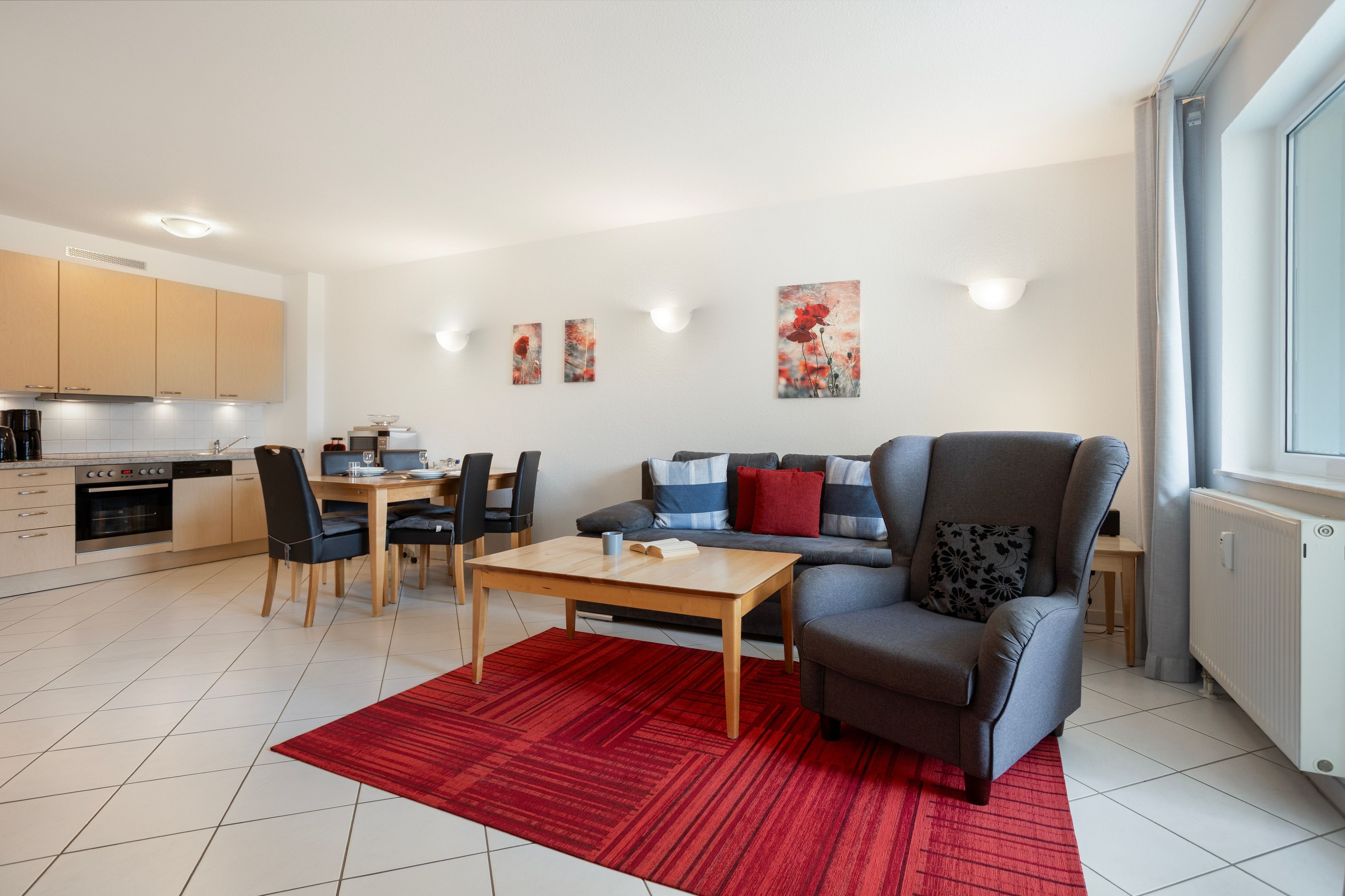 A modern living room with a sofa, a coffee table, and a dining area with chairs and a table.