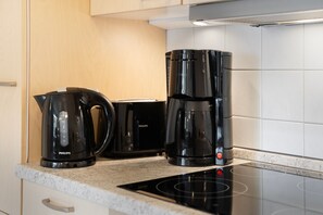Een keuken met een zwarte koffiezetapparaat, een broodrooster en een waterkoker op het aanrecht.