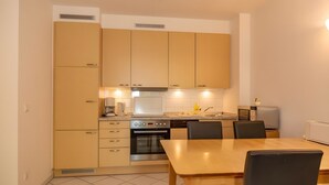 A compact kitchen with a dining table and chairs, a coffee maker, and a microwave. - Apartment '22 Anemone' with Balcony and Wi-Fi (Zempin)