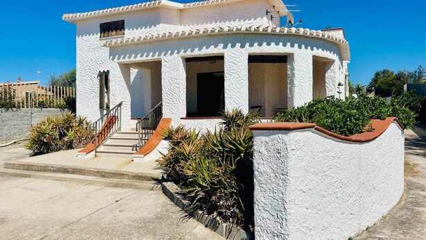 Un edificio de dos pisos con fachada blanca, un pequeño porche y una escalera que conduce a la entrada.