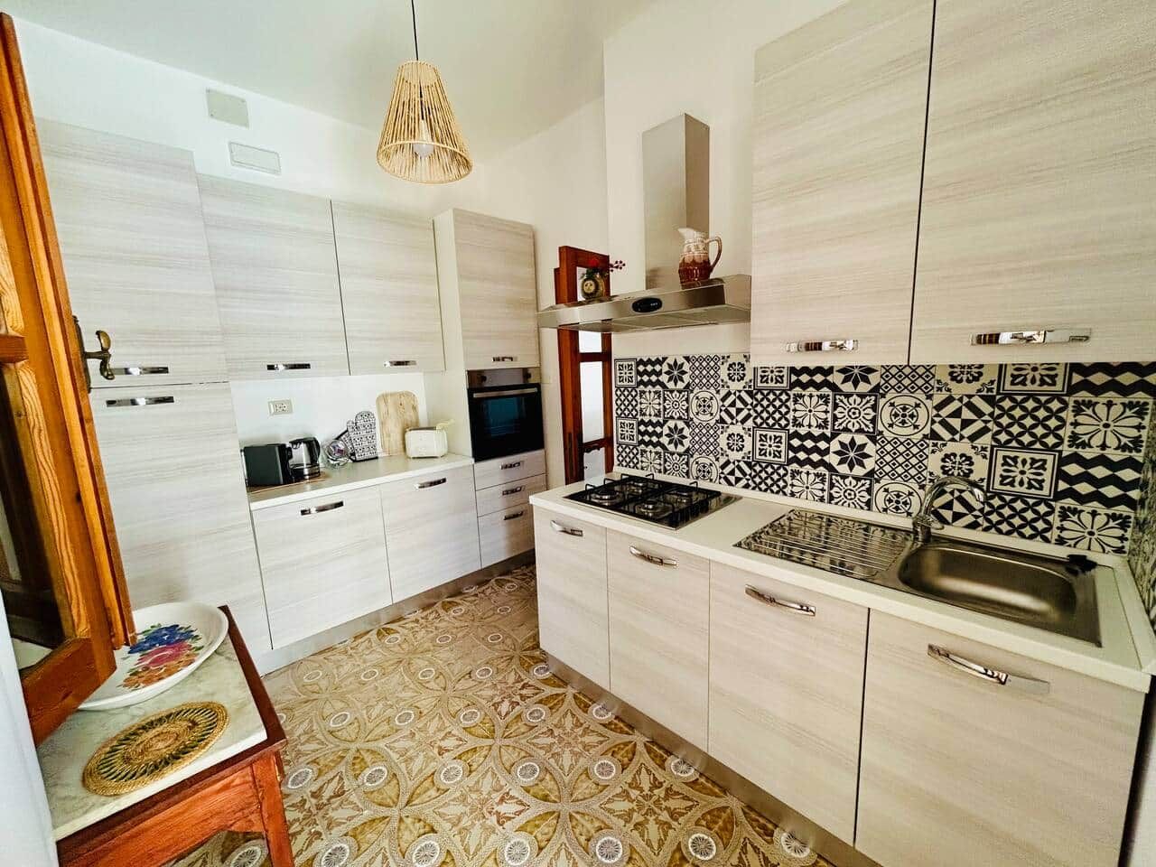 Une cuisine moderne avec des meubles blancs, un pare-feu décoré et une cuisinière à gaz.