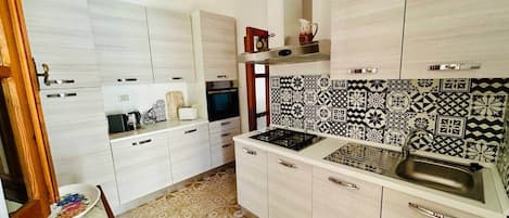 Una cocina moderna con armarios blancos, un salpicadero decorado y una estufa a gas.