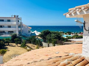 A coastal view with a building, a pool, and a clear sky.