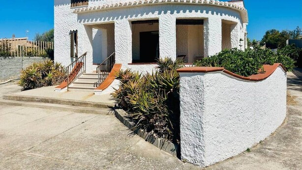 A two-story building with a white exterior, a small porch, and a staircase leading to the entrance. - Villa Maria - Detached home 150 meters from the sea (Eden Beach)