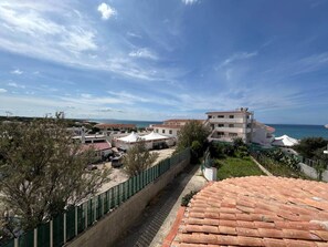 A coastal residential area with buildings, a paved walkway, and a view of the sea.