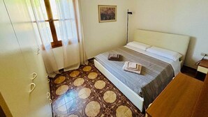 A bedroom with a bed, a nightstand, a picture on the wall, and a patterned floor. - Villa Maria - Detached home 150 meters from the sea (Eden Beach)