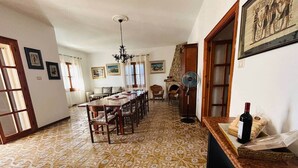 Un comedor con piso estampado, una mesa larga, sillas, una araña y una botella de vino sobre una mesa.