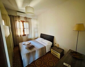 A hotel room with a bed, bedside table, lamp, and curtains.