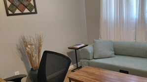 A furnished living room with a sofa, a coffee table, a chair, a small side table, and a decorative wall piece. - Quiet, peaceful home located near Fort Bragg and Cape Fear Medical Center (Fayetteville)