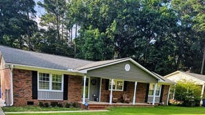 A two-story brick house with a front porch, a well-maintained lawn, and a clear sky. - Quiet, peaceful home located near Fort Bragg and Cape Fear Medical Center (Fayetteville)