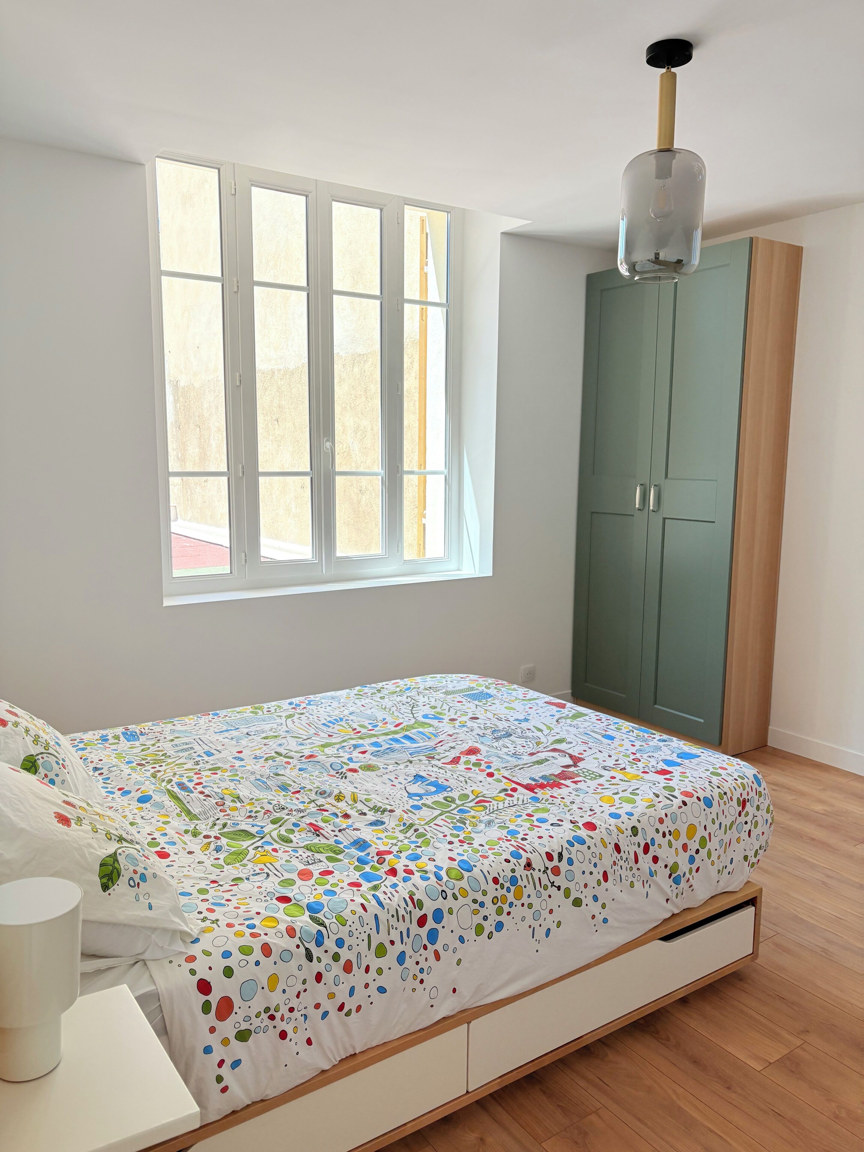 Une chambre à coucher avec un lit, une fenêtre, une armoire et un ventilateur de plafond.