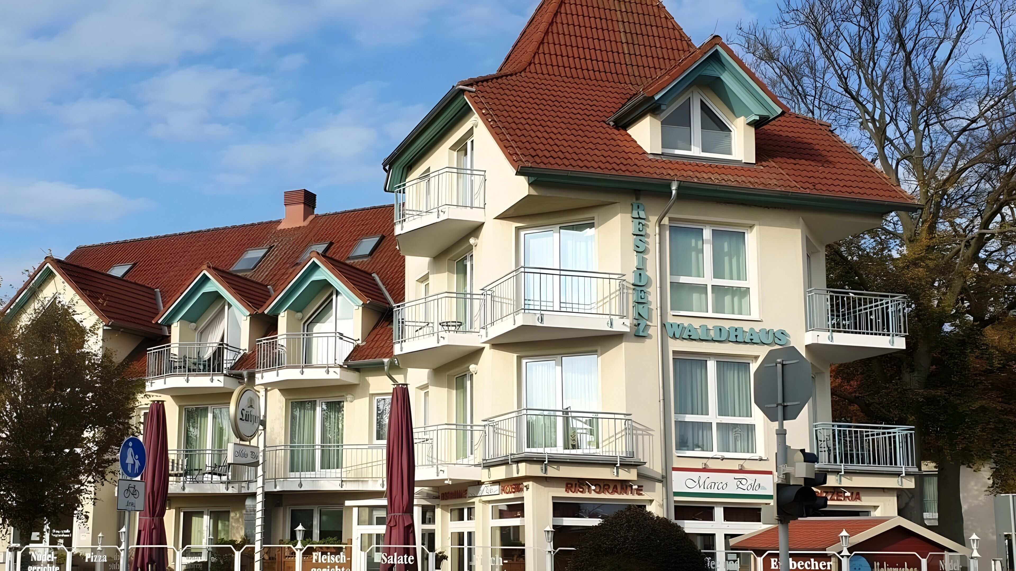 A multi-story building with balconies, a sign for 'WALDAUS,' and various storefronts including 'Ristorante' and 'Marco Polo.'