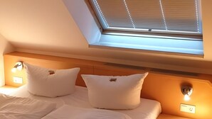 A bedroom with a sloped ceiling, a skylight, two bedside lamps, and a bed with white bedding. - Apartment for 4 People (44 m²) in Zempin (Seaside Resort) (Zempin)
