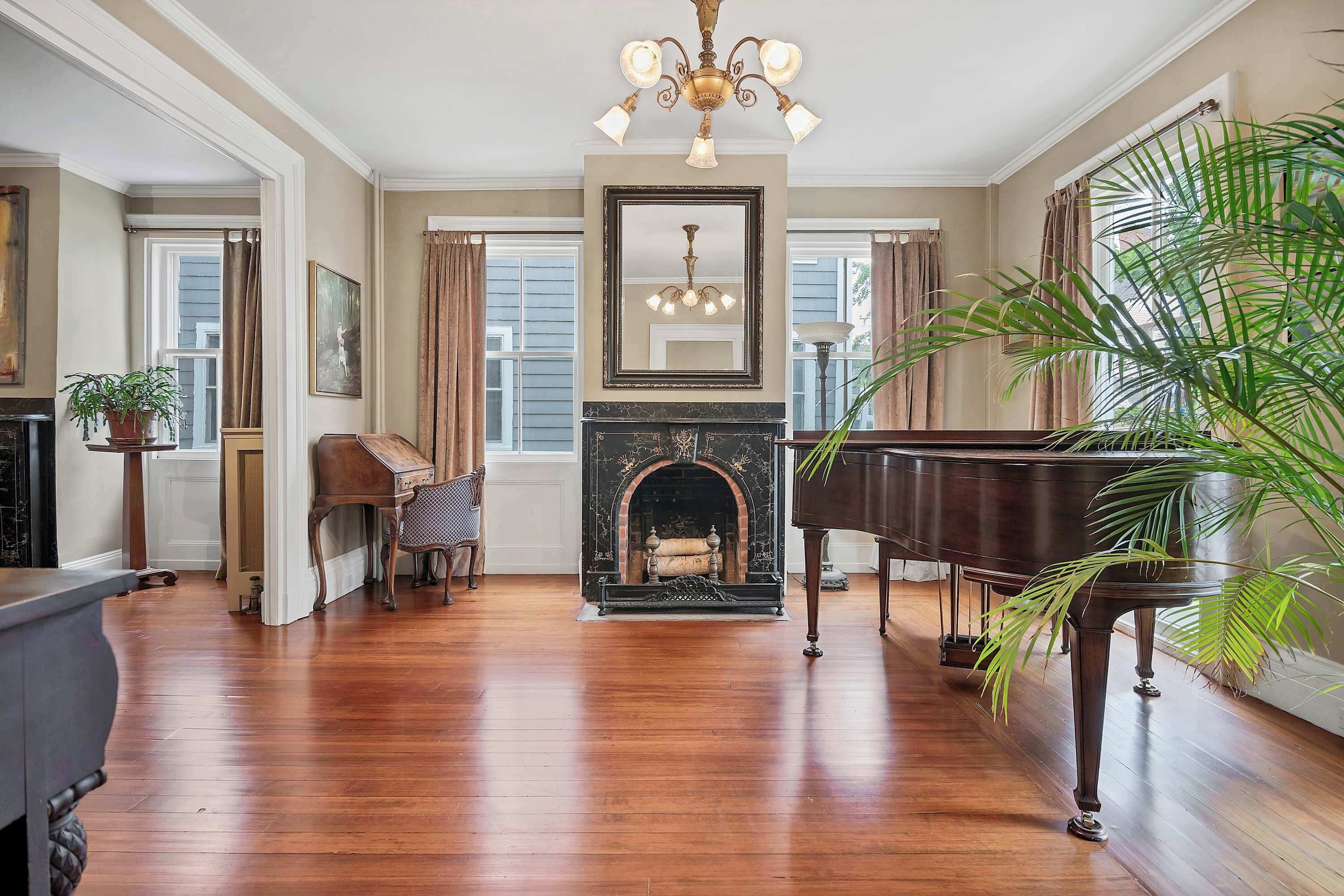 Une pièce spacieuse dot ée d’un parquet, d’un grand piano, d’une cheminée et d’un grand miroir.