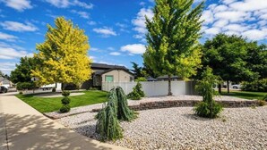 A residential area with a well-maintained lawn, a variety of trees, and a clear sky. - The Hive Hideaway (Meridian)