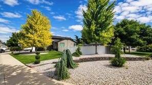 A residential area with a well-maintained lawn, a variety of trees, and a clear sky. - The Hive Hideaway (Meridian)