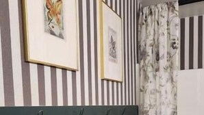 A bathroom with striped walls, a headboard with towels, and framed artwork. - The Hive Hideaway (Meridian)