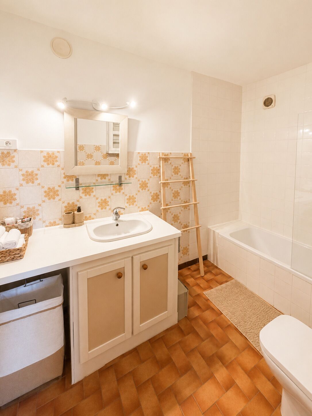 Une salle de bain avec un lavabo blanc, un miroir et une baignoire.