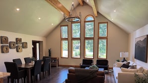 Un loft spacieux comprenant un coin repas, un espace salon et de grandes fenêtres offrant une vue sur l’extérieur.