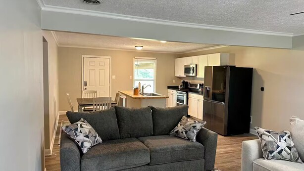 A living room with a sofa, a dining table, and a kitchen area with appliances.