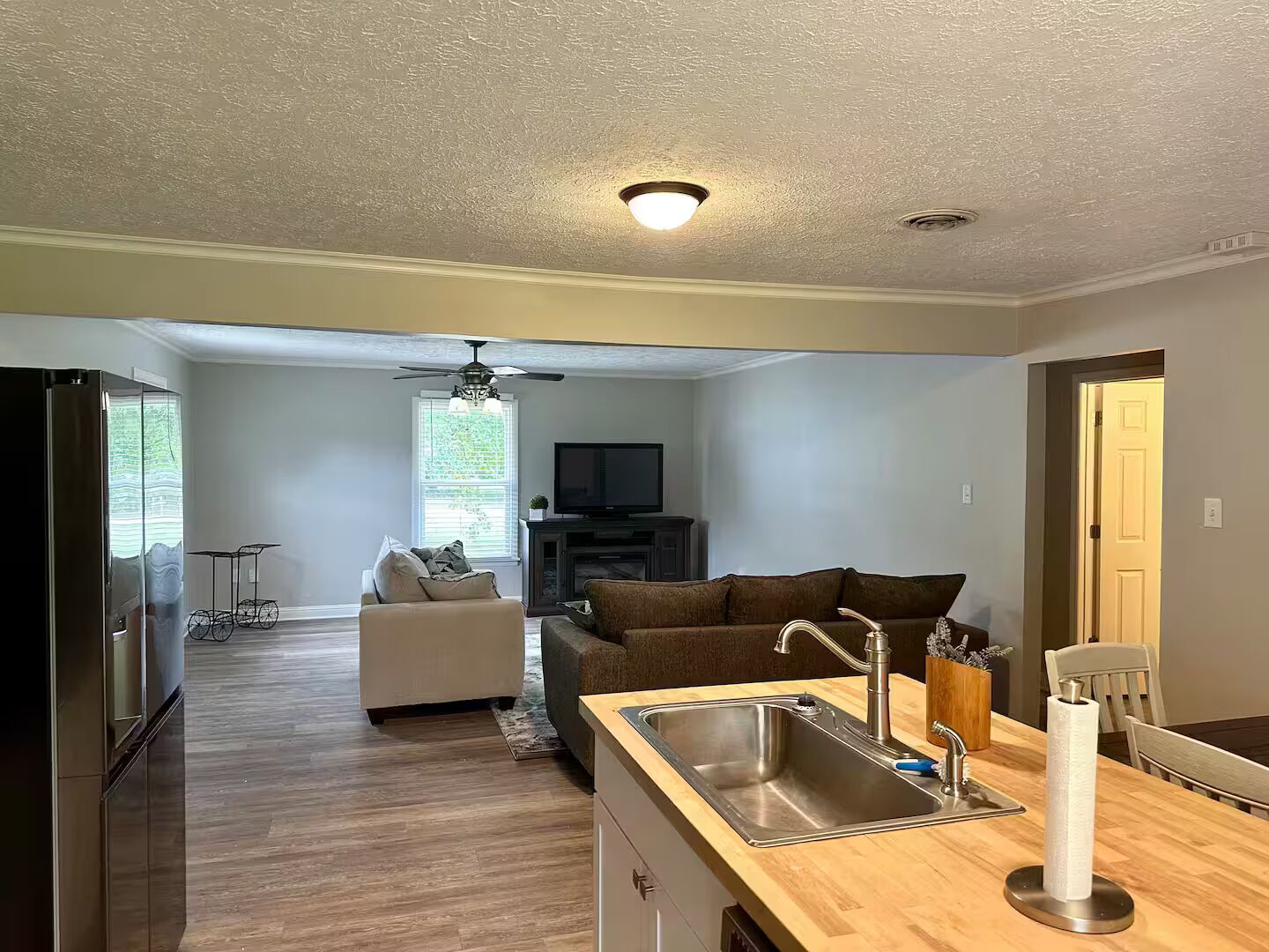 Una cucina moderna con piano di lavoro in legno, lavello in acciaio inox e ventilatore a soffitto.