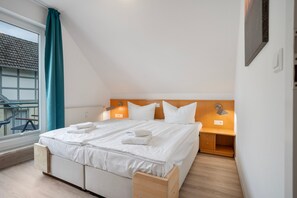 A bedroom with a bed, bedside tables, a window with curtains, and a view of the outside. - Apartment "Bernsteinfischer" with Balcony and Wi-Fi (Zempin)