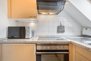 A modern kitchen with a built-in microwave, toaster, and oven. - Apartment "Bernsteinfischer" with Balcony and Wi-Fi (Zempin)
