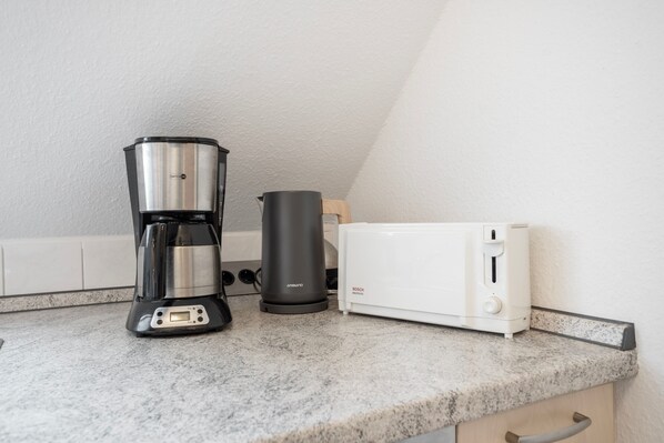 En köksbänk med en kaffebryggare, en vattenkokare och en brödrost.