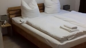 A neatly made bed with white bedding, a wooden headboard, and two bedside tables with lamps. - Strandidyll Apartment with Balcony and Wi-Fi (Zempin)