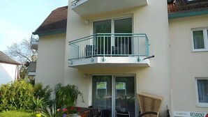 A residential building with a balcony, a sliding glass door, and a chair outside. - Strandidyll Apartment with Balcony and Wi-Fi (Zempin)